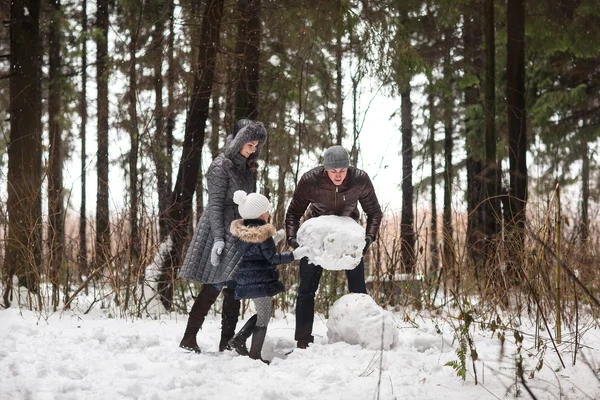 Familia feliz esculpe muñeco de nieve . — Foto de Stock