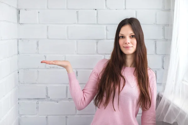 Beautiful woman stands on a brick background — Stock Photo, Image