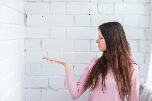 Beautiful woman stands on a brick background — Stock Photo, Image