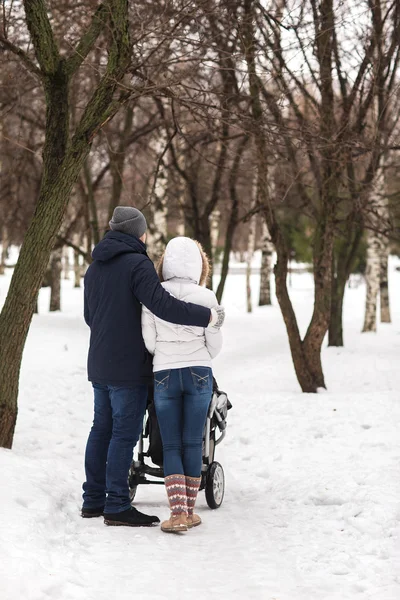 Счастливая молодая семья, гуляющая в парке зимой — стоковое фото