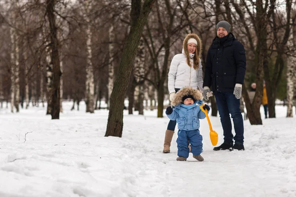 Счастливая молодая семья, гуляющая в зимнем парке — стоковое фото