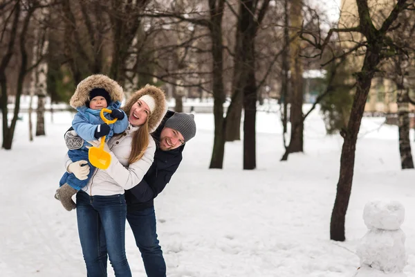 Счастливая молодая семья, гуляющая в зимнем парке — стоковое фото