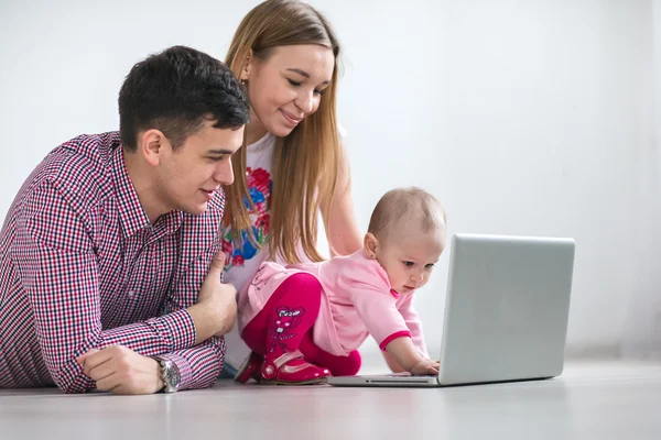 Joven familia feliz corriendo en un ordenador portátil —  Fotos de Stock