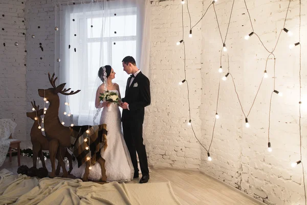 Beautiful young bride and groom embracing in the New Year interi — Stock Photo, Image