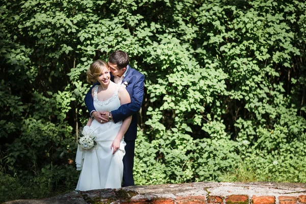 Happy bride and groom walking in the summer forest. — Stock Photo, Image