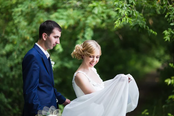 Lyckliga bruden och brudgummen promenader i skogen sommaren. — Stockfoto
