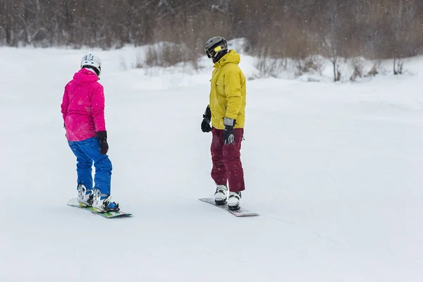 Pareja joven snowboarders deslizarse hacia abajo — Foto de Stock
