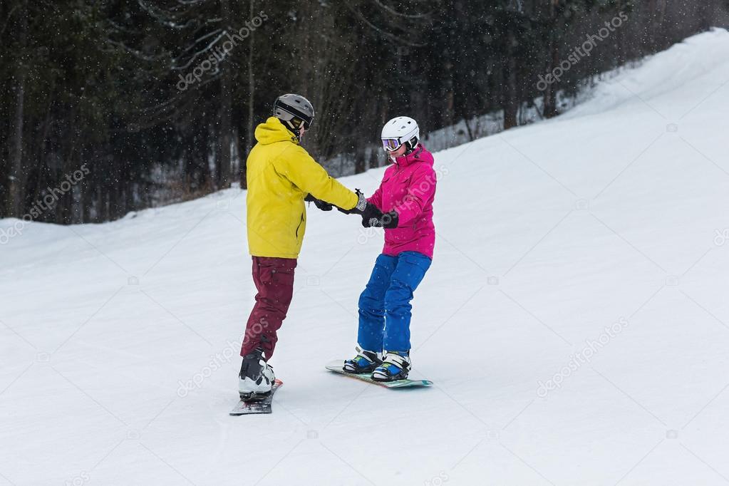 Young couple snowboarders slide down