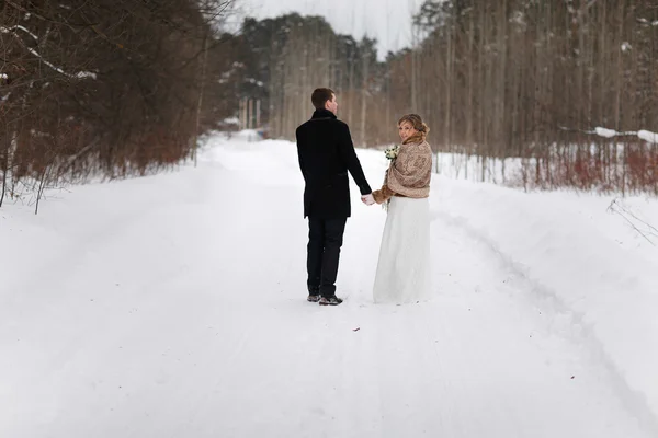 Young couple newlyweds walking in a winter forest in the snow. — Stock Photo, Image