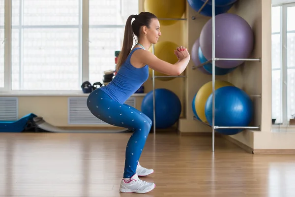 Young fitness woman doing squats — Zdjęcie stockowe