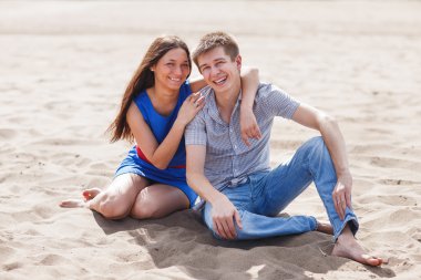 A young couple walks along the beach.