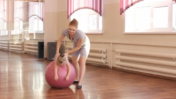 Pregnant woman with her first kid daughter doing gymnastics