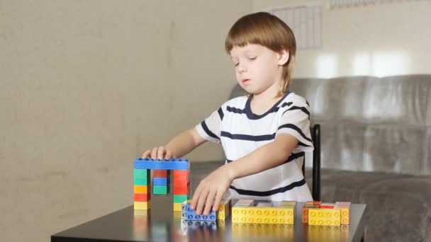 Garçon jouer avec beaucoup de blocs en plastique coloré à l'intérieur — Video