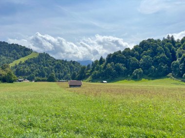 Tepeler boyunca uzanan bir dağ yerleşiminin yakınındaki geniş bir yolun manzarası güneşli, hafif bulutlu bir gökyüzünün arka planına karşı..