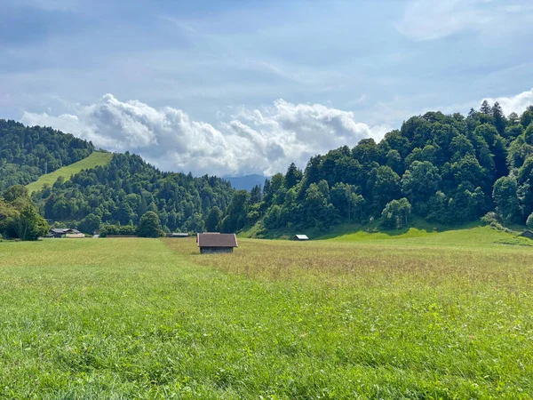 Tepeler boyunca uzanan bir dağ yerleşiminin yakınındaki geniş bir yolun manzarası güneşli, hafif bulutlu bir gökyüzünün arka planına karşı..