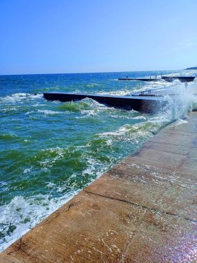 Langeron 'un taştan seti üzerindeki gök mavisi kıyı dalgalarının büyüleyici manzarası güneşte parlayan soğuk spreyleri saçıyor..