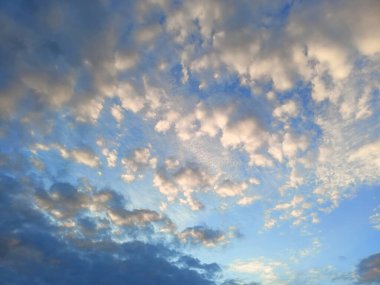 Gün batımının renkleriyle boyanmış bulut desenli gökyüzü manzarası.