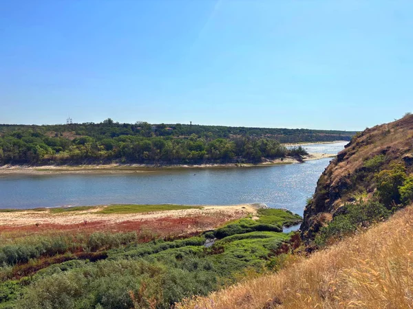 Dinyeper nehir yatağının şaşırtıcı manzarası. Etrafı yoğun sedir ve sazlıklarla çevrili. Güneşli bir yaz gökyüzünün arka planında Baida adasını yıkıyorlar..