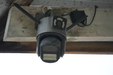 Kızıl ötesi ışıkları olan siyah ve gri bir güvenlik kamerası ahşap bir kirişe monte edilmiştir..