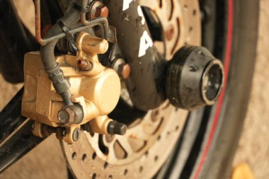 Motosikletin fren kalibre ve tekerleğinin detaylı görüntüsü, mekanik bileşenleri ve dokuları gösteriyor.