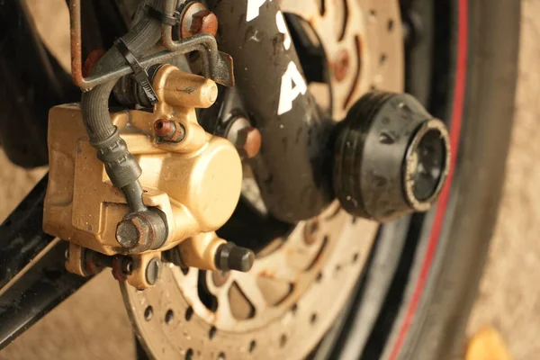 Motosikletin fren kalibre ve tekerleğinin detaylı görüntüsü, mekanik bileşenleri ve dokuları gösteriyor.