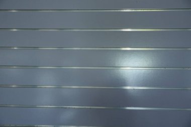 Yansıtıcı bir yüzeye sahip gri metalik levhaların yakın plan görüntüsü, yatay çizgilerden oluşan bir desen ve endüstriyel arkaplan veya doku olarak kullanılabilecek ince bir parlaklık sergiliyor..