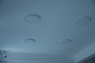 Köşesinde dört ışık ve bir güvenlik kamerası olan beyaz bir tavan güvenli ve modern iç tasarım hissi veriyor..