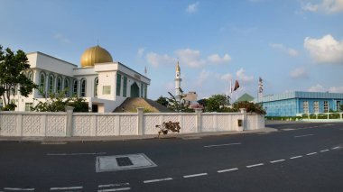 Parlayan altın bir kubbe ve yükselen bir minarenin yer aldığı bu beyaz caminin ihtişamı açık mavi gökyüzüne karşı duruyor..