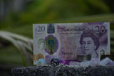 10 kiloluk banknot, madeni paralar ve çeşitli kristallerle çevrili, yumuşak, bulanık doğal bir zemin üzerine kurulmuş bir odak noktasıdır..