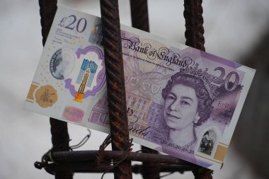 20 pound 'luk banknot, inşaat, altyapı veya kentsel kalkınma alanlarında finansmanı temsil eden paslı bir inşaat demirinin içine dikkatlice yerleştirilir..