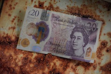 20 poundluk banknotun canlı renkleri, endüstriyel bozulma ortasındaki finansal istikrarın sembolü olan ağır metal korozyonuna karşı çıkıyor..