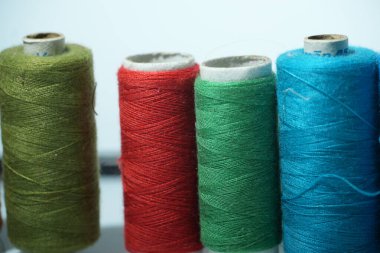 Yeşil, kırmızı ve mavi tonlarında iplik makaralarının net ve detaylı bir görüntüsü, tekstil projeleri için mükemmel..