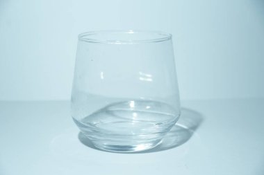 Boş, berrak yuvarlak bir bardağın basit, zarif bir görüntüsü, boşluk ve basitlik kavramlarını göstermek için mükemmel..