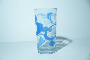 Bu resim, göz alıcı mavi dairesel desenlere sahip, şık, boş, uzun bir bardağı gösteriyor..