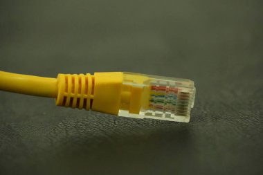 Bu resim, modern veri ve internet bağlantısını sembolize eden RJ45 bağlantısını açıkça gösteren parlak sarı bir ethernet kablosuna odaklanır..