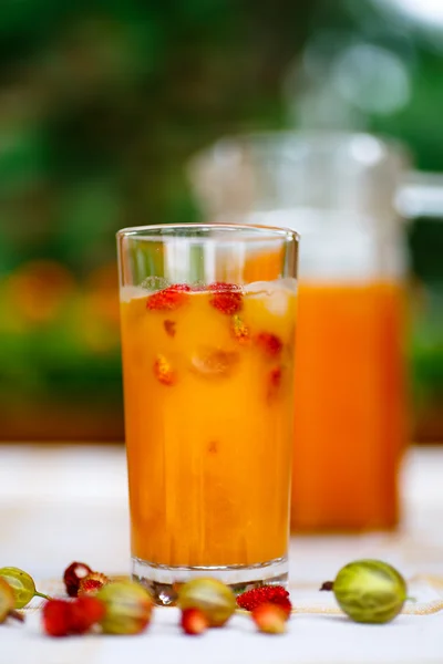 Napój pomarańczowy przelewa się do karafki i szkła. — Zdjęcie stockowe