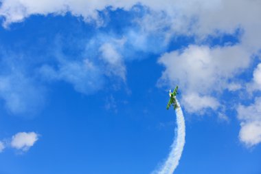 Little green plane performs aerobatics in the sky. clipart
