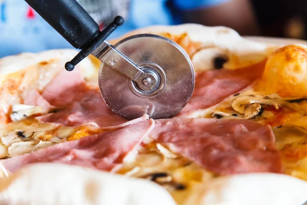 Круглый нож режет пиццу ветчиной . — стоковое фото