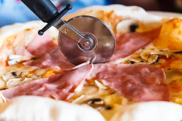 Круглый нож режет пиццу ветчиной . — стоковое фото