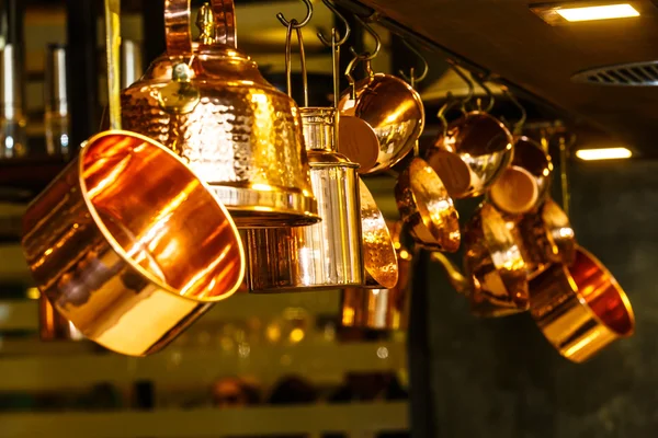 Copper kitchenware (pots, pans, jugs) hang from the ceiling in t — Stock Photo, Image