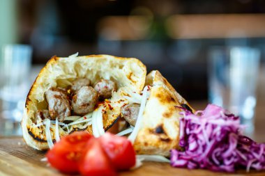 Kebap bir pide, domates ve kırmızı lahana yalan soğan ile.