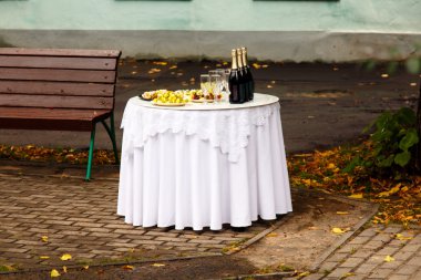 Şişe şampanya ve aperatifler are üstünde beyaz yuvarlak masa t