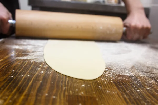 Preparation of the dough. Cook rolls out the dough on the Board. — Stock Photo, Image