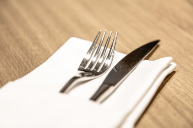 Restoranda katlanmış beyaz peçeteye çatal ve bıçak yalan.