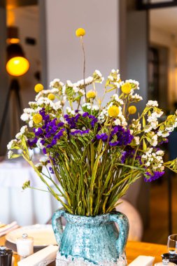 Masanın üzerinde bir buket kurutulmuş mavi ve beyaz renkli çiçek var.