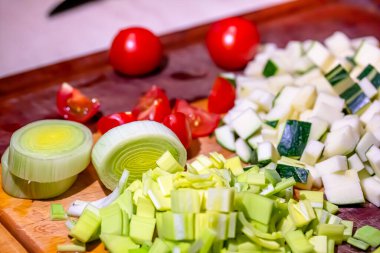 Aşçı kabakları, pırasaları ve domatesleri kızartmak için küçük küplere ayırır.