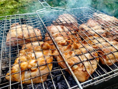 Salamura edilmiş tavuk parçaları ızgarada pişiyor.