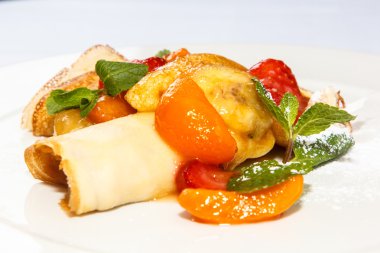 Krep meyve ile pudra şekeri serpilir ve üzerinde meyveleri vardır 