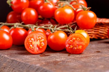 Kırmızı domates karanlık bir tablo üzerinde bir sepet içinde yatan Şubesi.