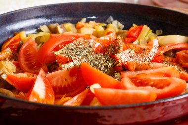 Pişirme sebze güveç, domates kuru otlar ile serpilir.